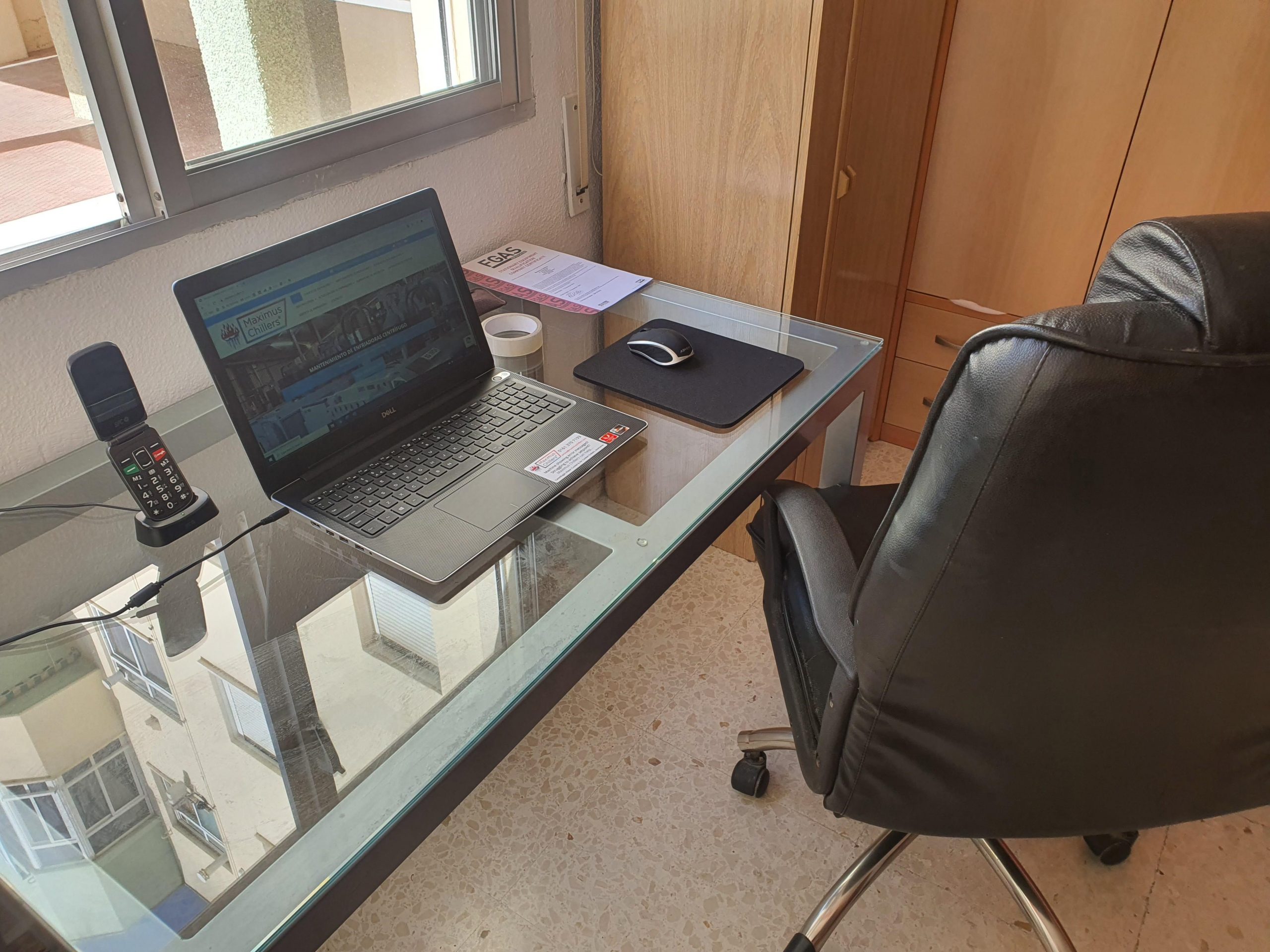 La Oficina Española 2 Un escritorio de cristal, portátil y silla ejecutiva en la oficina española