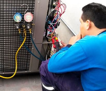 Ingeniero con manómetros y amperímetro en la unidad de climatización